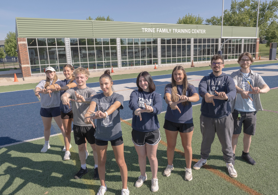 students forming a lightning bolt in front of the trine family training center
