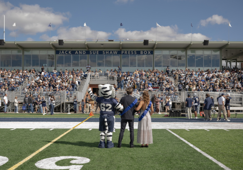 homecoming king and queen face audience with mascot storm