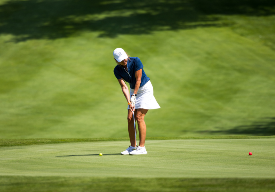 woman watches her golf ball near the hole