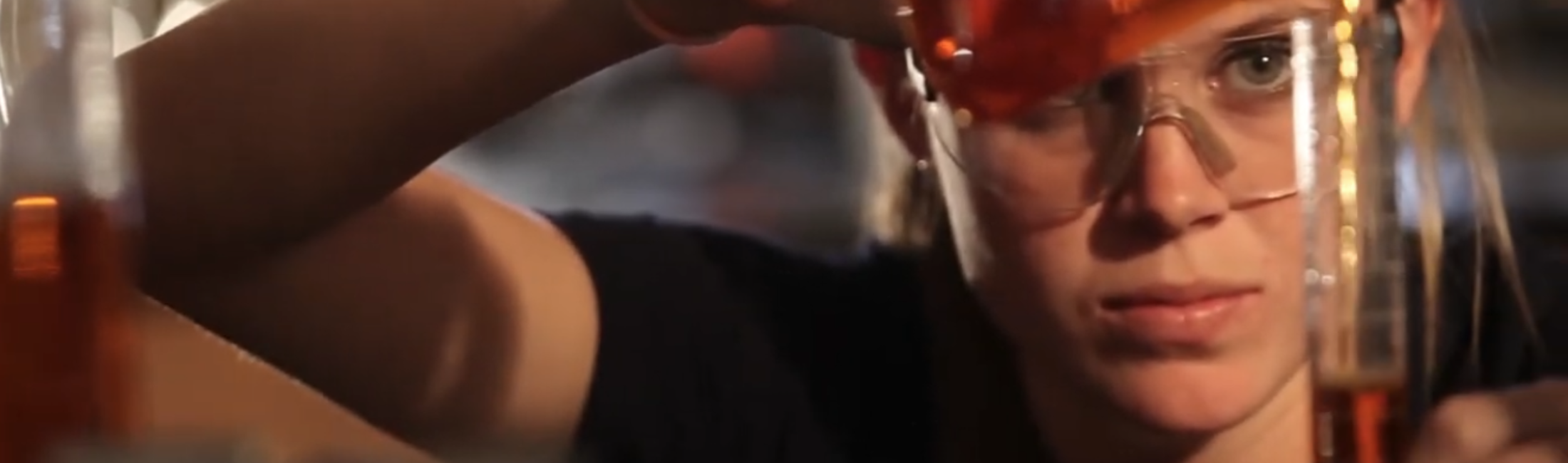 student pouring liquid into a beaker