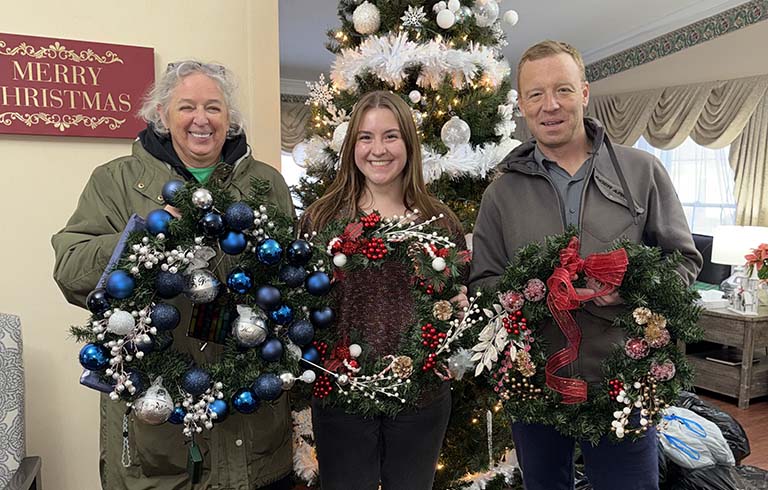 Three Trine University staff with Christmas wreaths