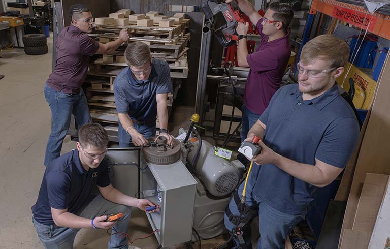 Trine University students working on Dexter Axle pallet squeezer