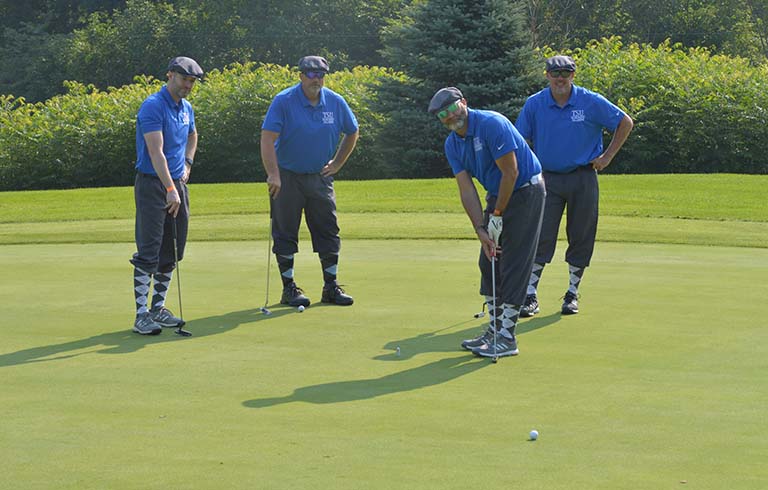 Golfer putting as three others look on