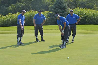 Golfer putting as three others watch