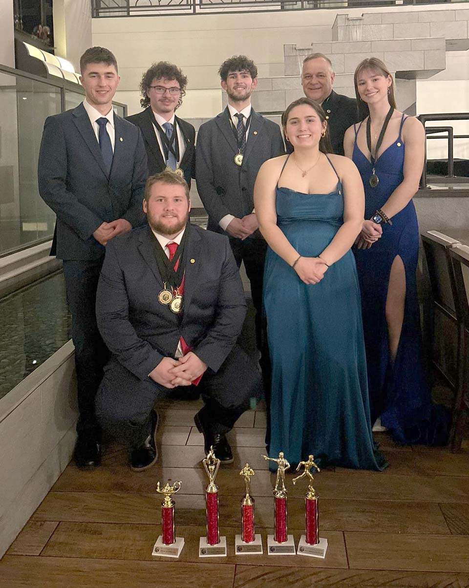 Six students and faculty advisor with trophies