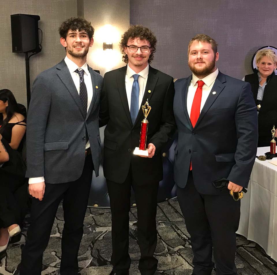 Three male students with trophy