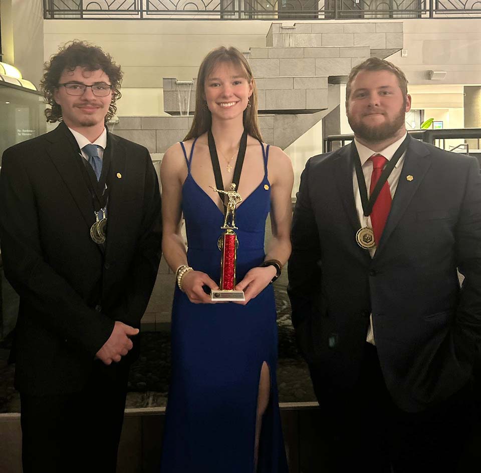 Two male students and one female student with trophy