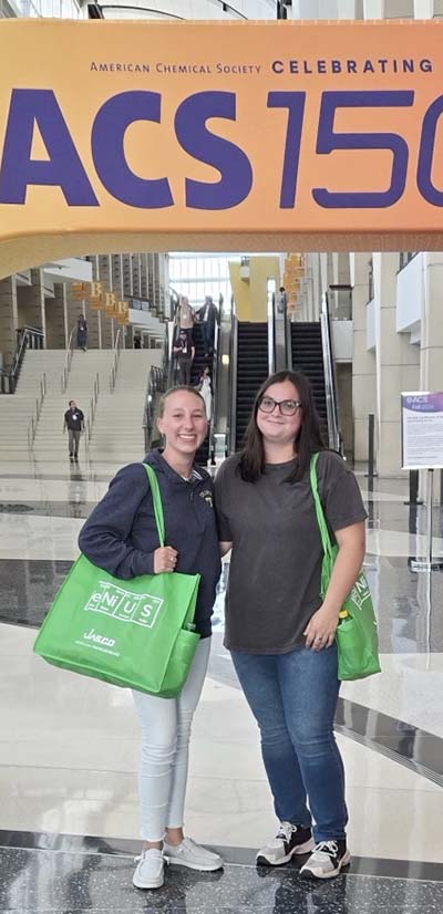 Two female students under ACS 150 arch