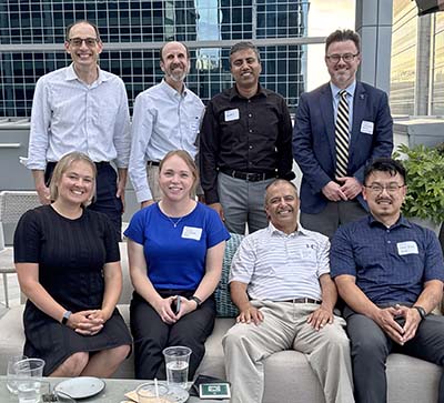 Eight faculty members, four seated in front and four standing behind.