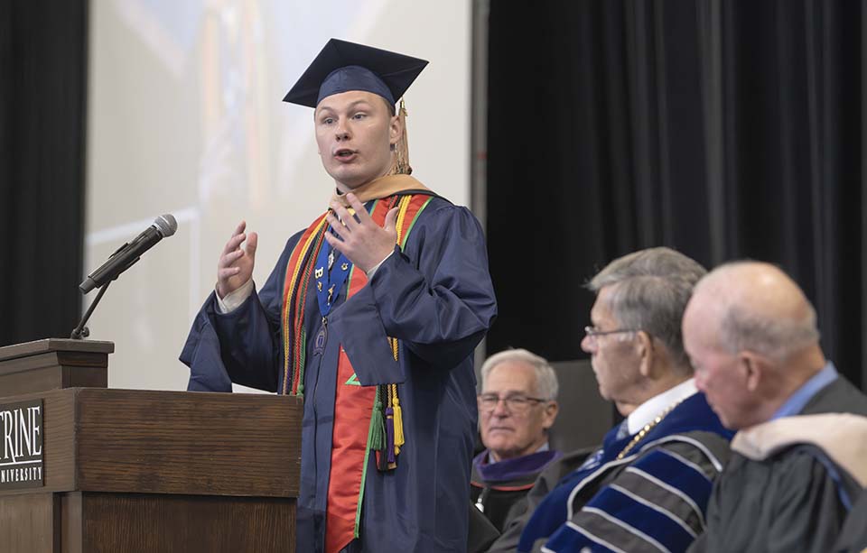 Student in Commencement regalia speaking at podium
