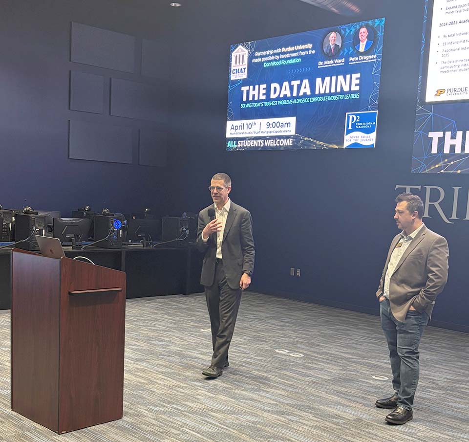 Two men speaking in front of screen that reads "The Data Mine"