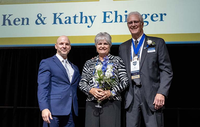 Dr. Kline, Kathy and Ken Ehinger in front of large screen.