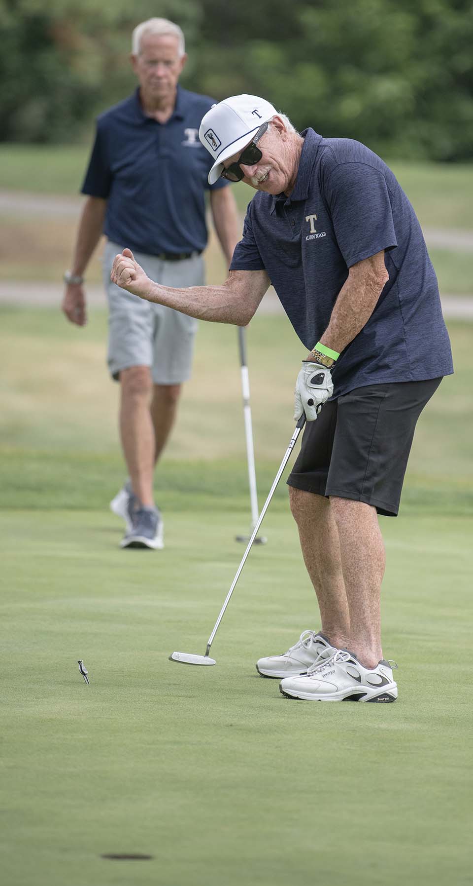Golfer pumping fist as another watches in the background