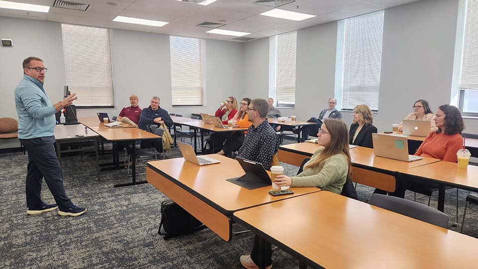 Trine professor at left speaking to classroom of local educators