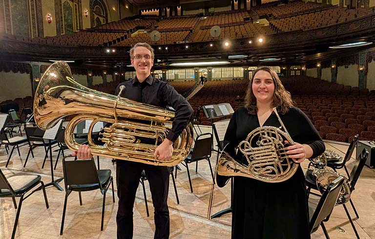 Male student with tuba and female student with French horn on the stage of the Embassy Theatre