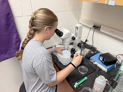 Female student looking through microscope