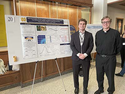 Keiton Klein and Fr. Bryan Paulsen, S.J., Ph.D., stand next to a research poster
