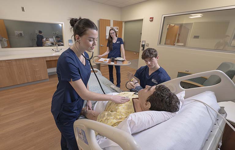 Three nursing students with manikin