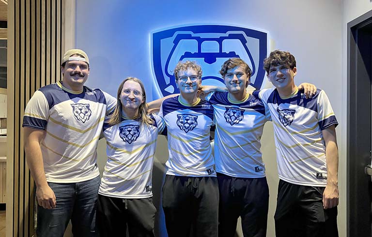 Five esports team members standing in front of stylized bulldog esports logo.