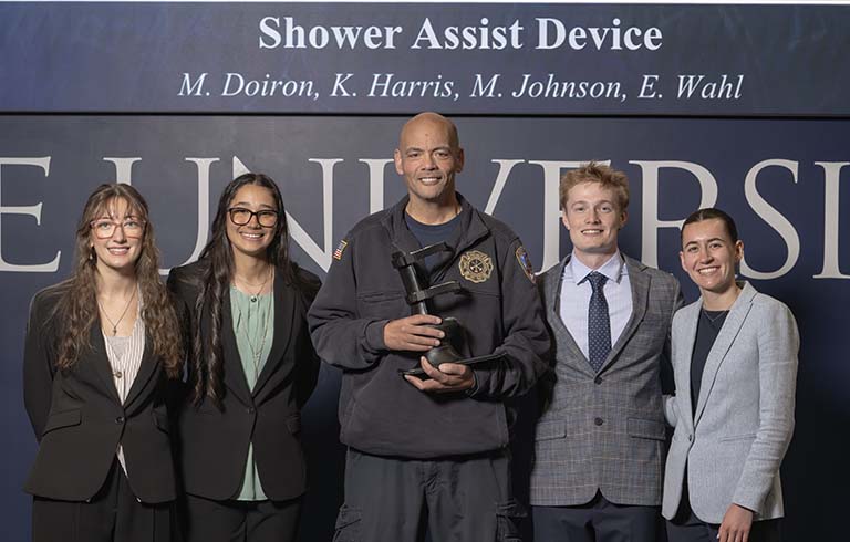 Four students with paramedic Ben Masten, who is holding the prosthetic