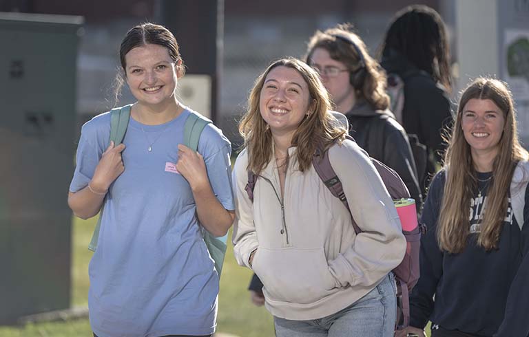 Smiling students walking across campus